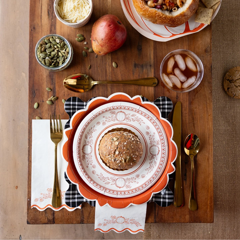 Fall place setting with pumpkin plates, gold flatware, and pumpkin guest napkins