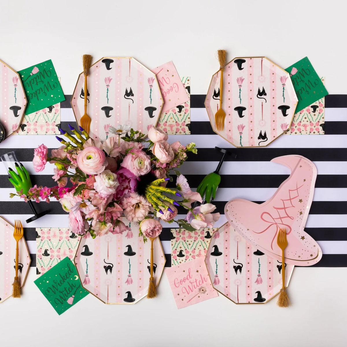 Overhead table with pink and green witch napkins styled with witch hat plates
