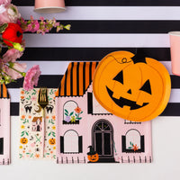 Place setting with jack-o-lantern pumpkin paper plates on pink haunted house theme, stylish Halloween plates
