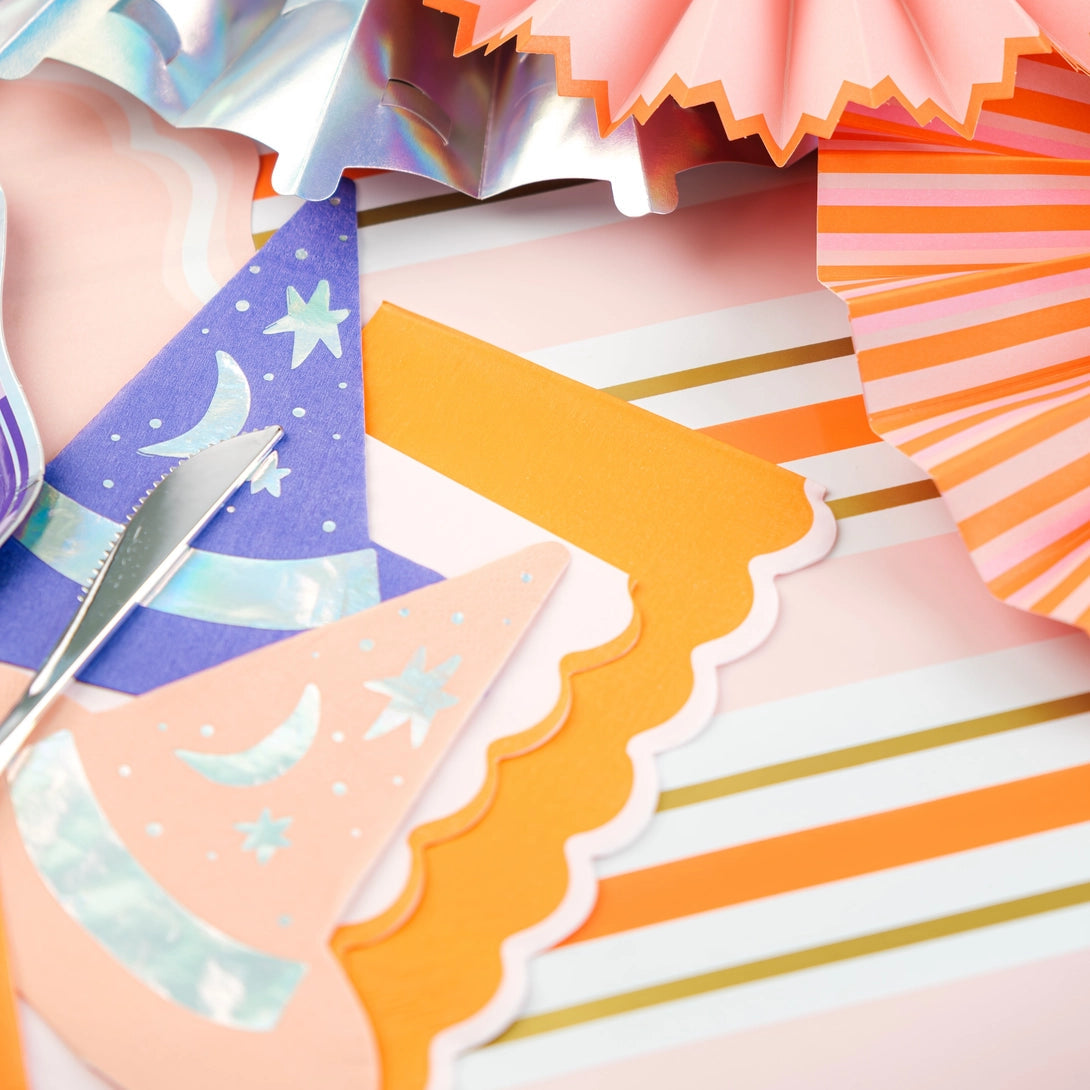 Close up of party fans and napkins on the orange and pink striped runner