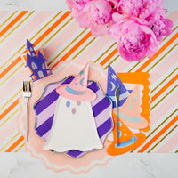 Place setting with ghost plate and witch hat napkins over striped paper table runner