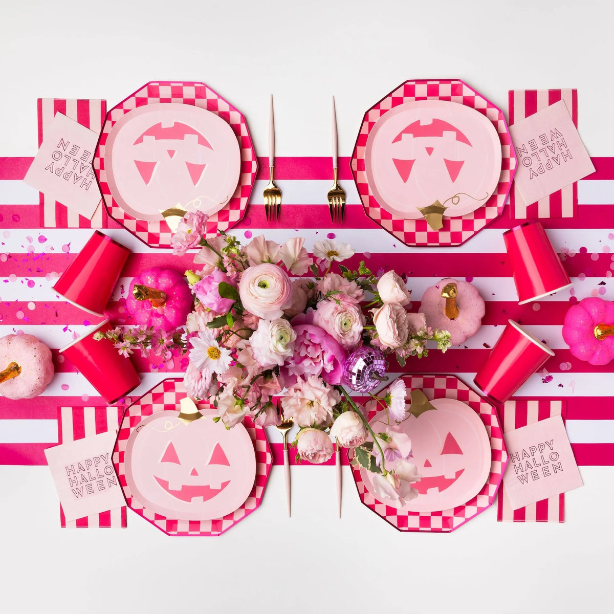 Overhead tablescape with pink jack o lantern pumpkin paper plates, flowers, and stripes, cute pink halloween decor