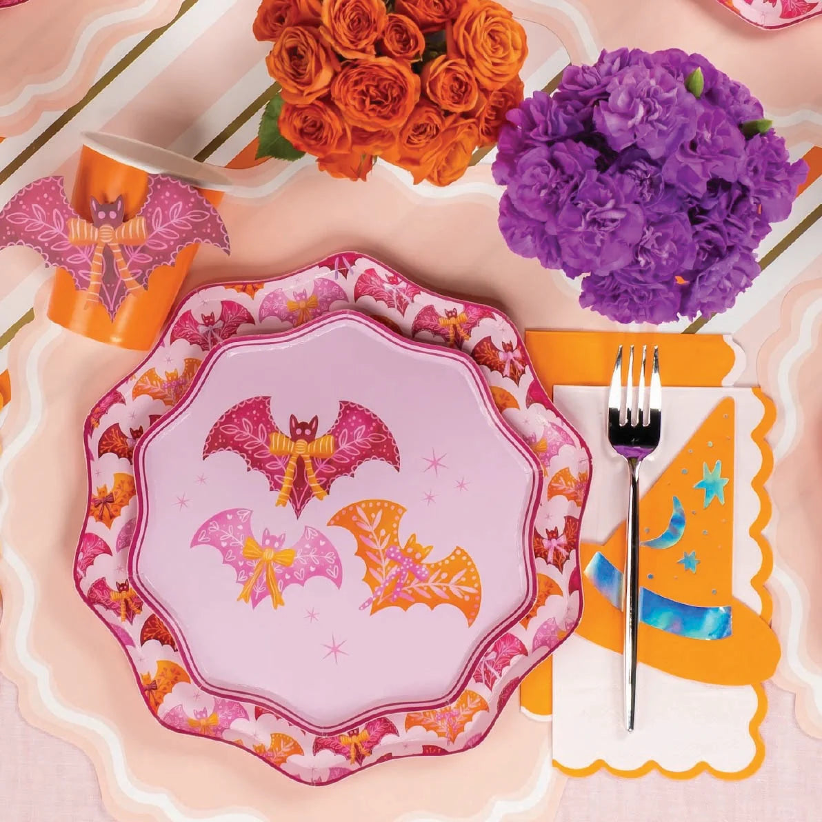 Close place setting with bat plate over blush paper placemats and orange napkin