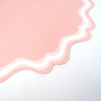 Closeup of scalloped edge on blush paper placemats with double white lines