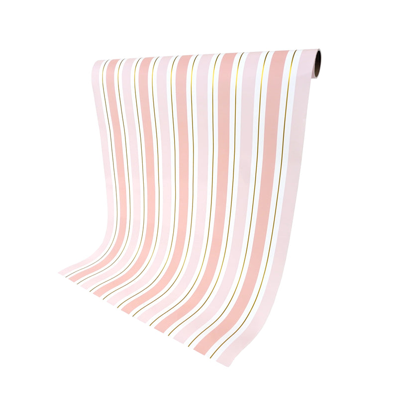 Unrolled pink striped table runner hanging from roll, gold foil stripes visible