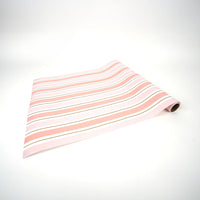 Pink striped paper table runner unrolled flat on white surface