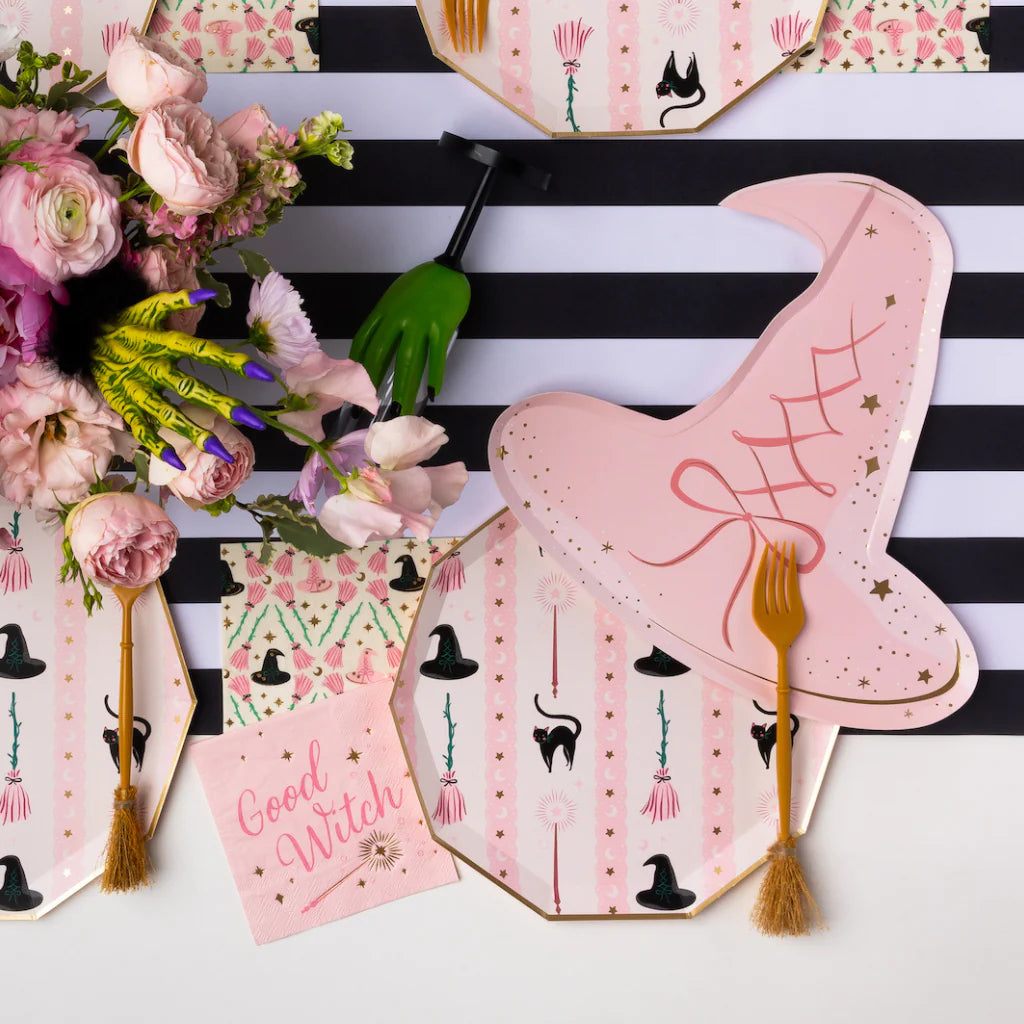 Close view of pink witch hat paper plates with striped runner and flowers