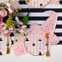 Close view of pink witch hat paper plates with striped runner and flowers