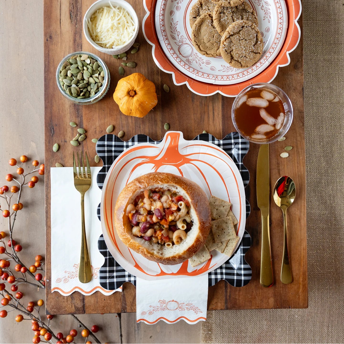 Tablescape with plaid charger under pumpkin plate and gold flatware