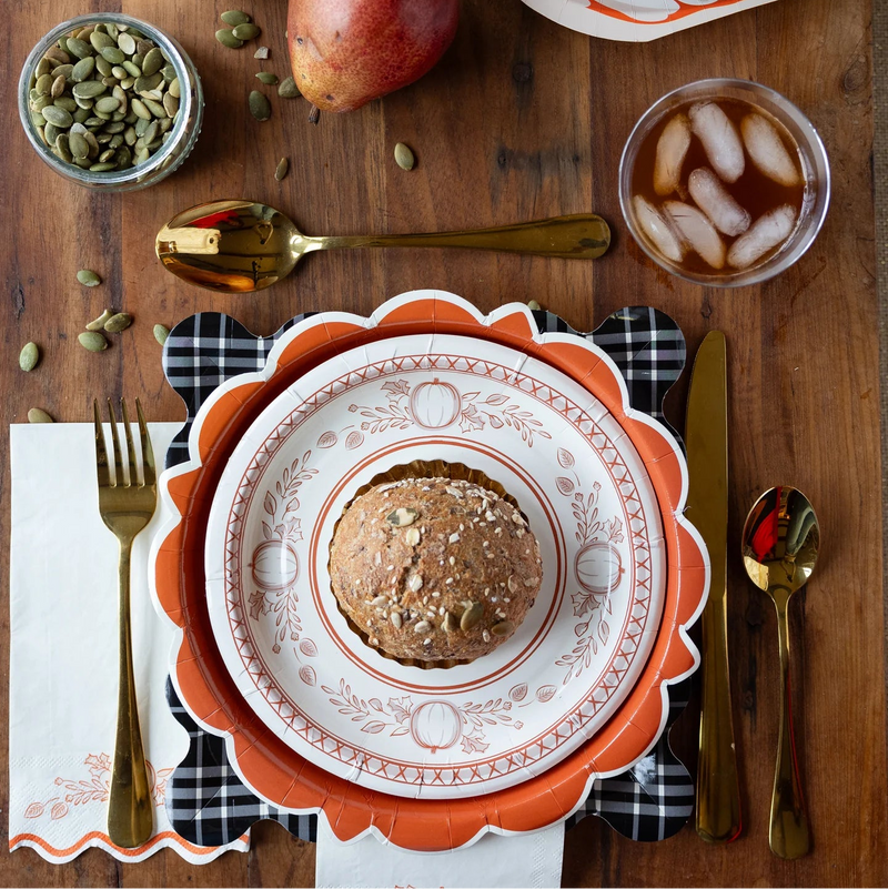 Dessert plate with a food, surrounded by gold cutlery, a glass of iced tea, and a pear on a wooden table.