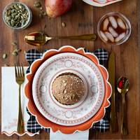Happy Harvest pumpkin paper plates layered with coordinating fall dinnerware, soup bowl, and seasonal decorations on a rustic wooden table.