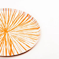 Angled view of Radiance orange dinner plate with sketchy sunburst lines