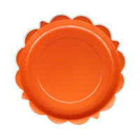 Single rust orange scalloped round plate on white background