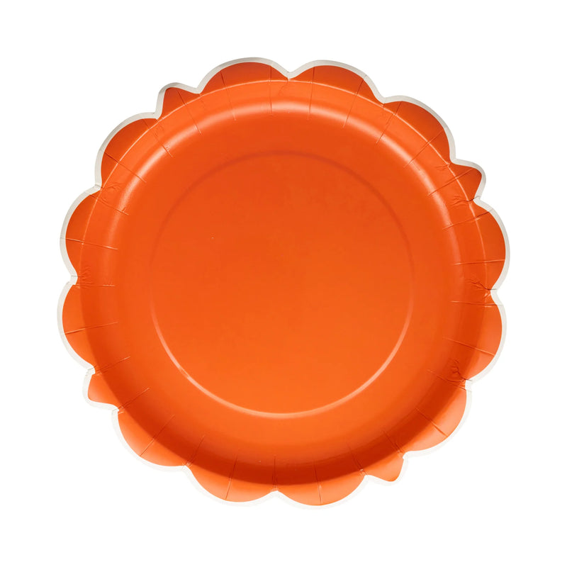Single rust orange scalloped round plate on white background