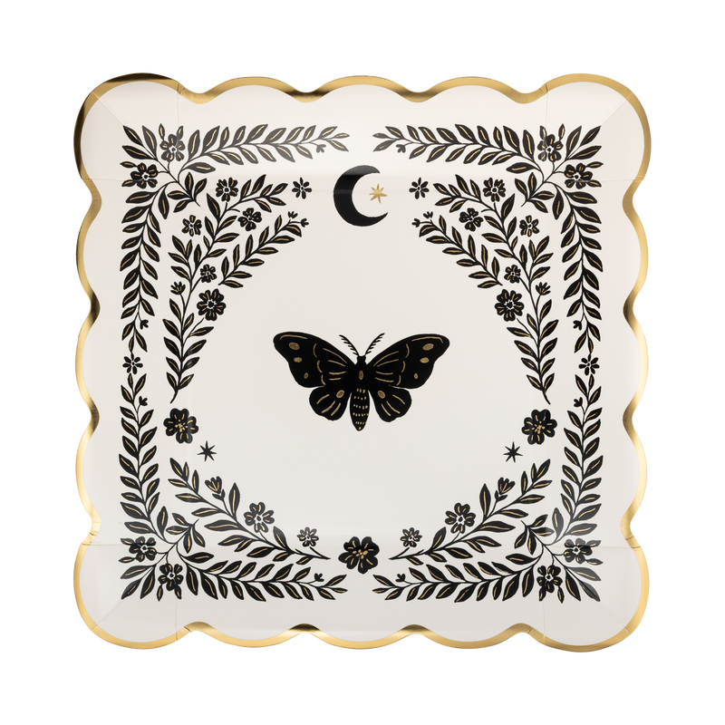 Top view of cream moonlight moth square paper dinner plate with gold foil scalloped edges and black botanical illustration against white background.