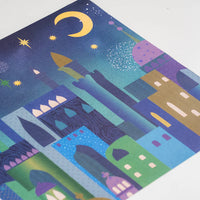 Paper placemat with a colorful cityscape illustration with buildings and a moon on a blue background