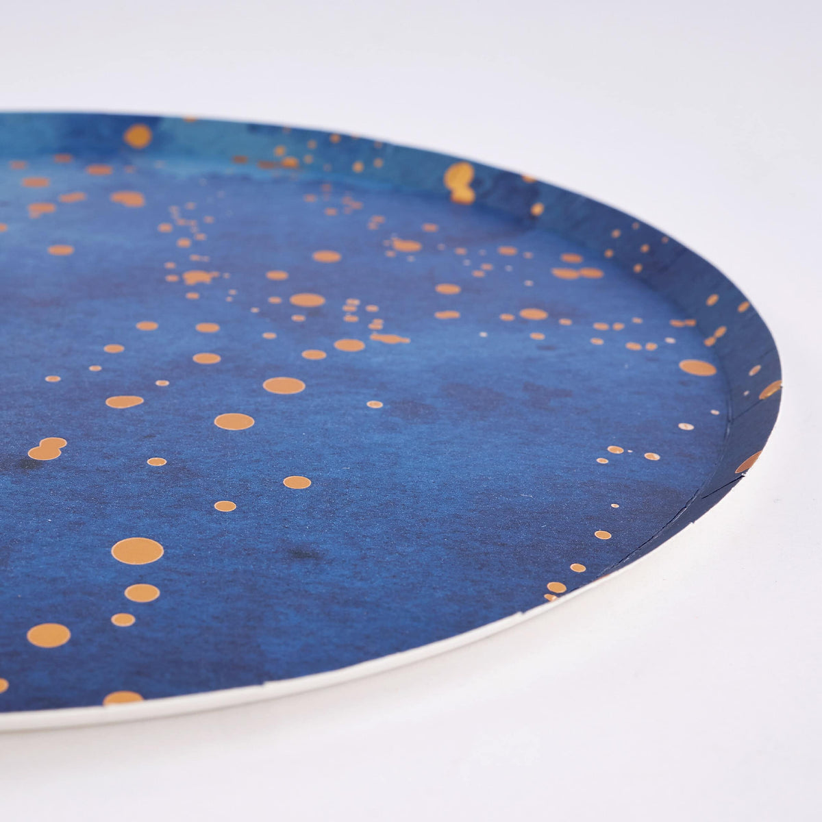 Angled edge detail of a navy watercolor plate with gold-foil dots