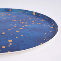 Angled edge detail of a navy watercolor plate with gold-foil dots