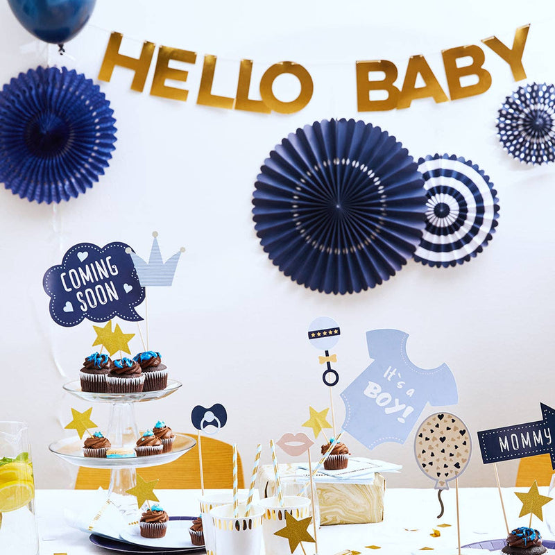 Classic navy and gold baby shower backdrop with navy party fans, "Hello Baby" banner, and "It's a Boy" cupcake display.