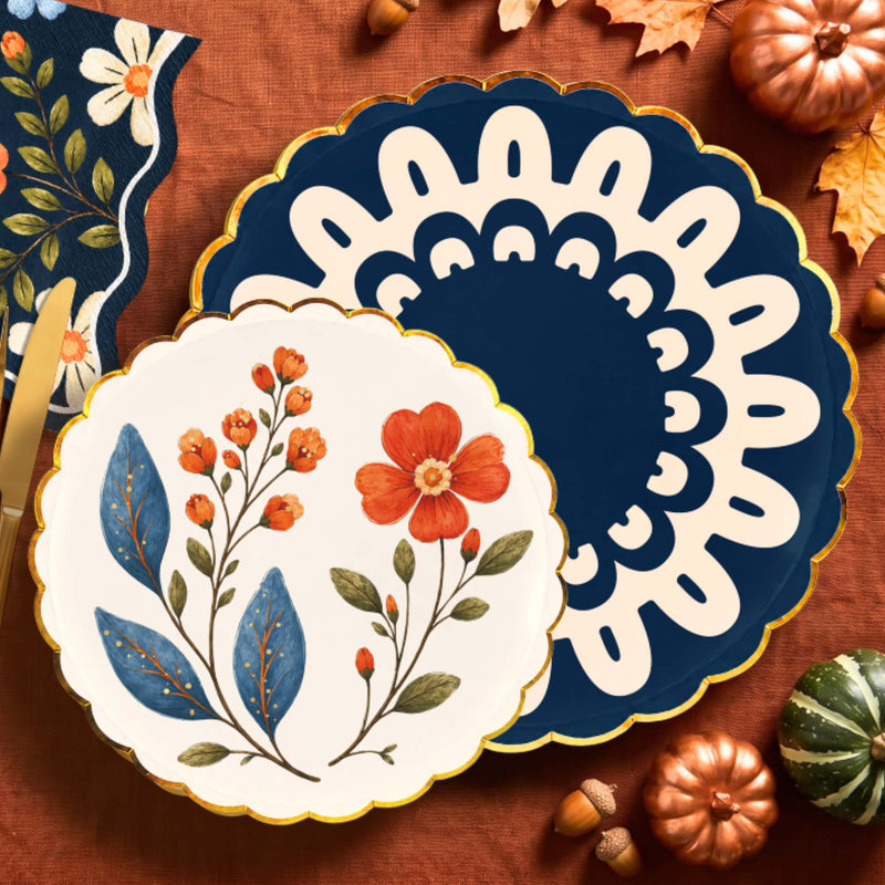 Navy doily dinner plate under a cream wildflower dessert plate on rust linen with copper pumpkins
