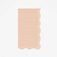 Solid light brown guest towel in warm tan with a flowing scalloped white-outlined edge, flat view on white background.