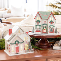 Collection of three Christmas village houses on a coffee table with a tree, including the Santa's House village piece.