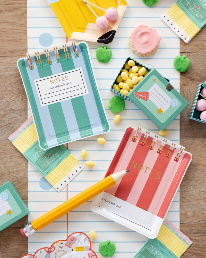 Notebook notepad paper plates and pencil napkins styled on notebook paper table runner with lunchbox treat boxes, cookies, and candies