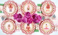 Overhead of pink nutcracker and drum plates on plaid plates around a bunch of pink peonies.