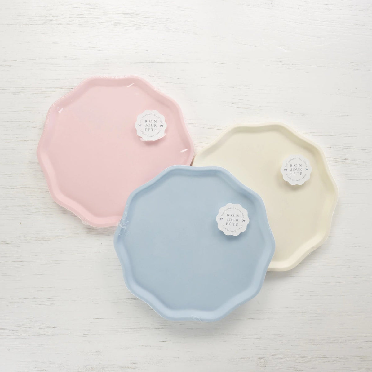 Packaged compostable plates in petal pink, sky blue, and cream—Bonjour Fête Signature Line.