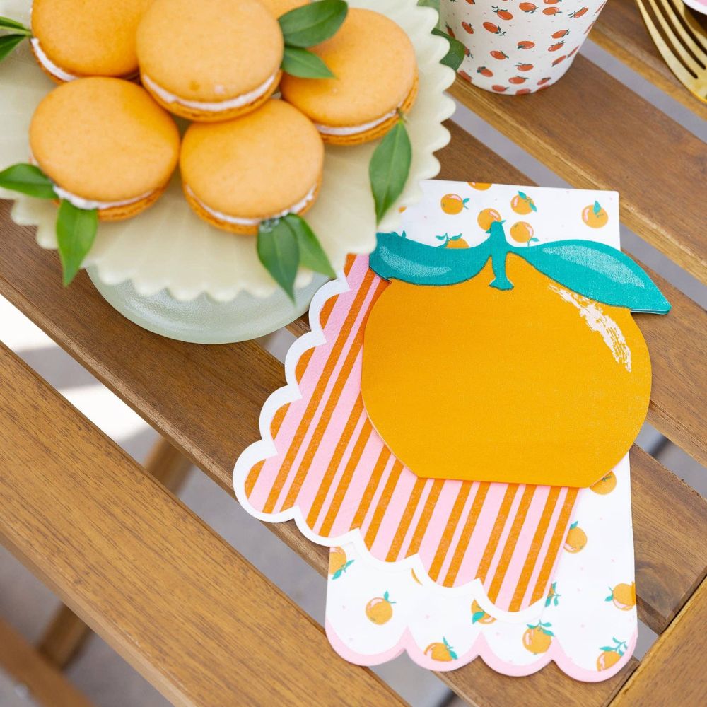 Orange shaped cocktail napkins styled on a citrus-themed party table.
