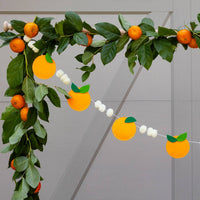 Orange felt banner draped across greenery for a summer party setup.