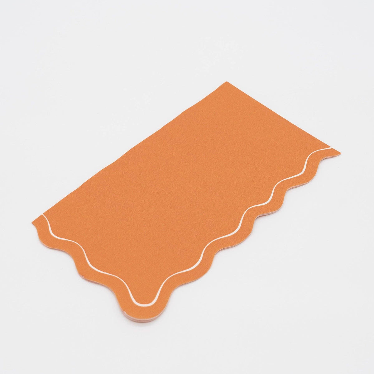 Two folded orange scalloped guest towels stacked, showing the wavy edge and cream outline detail.