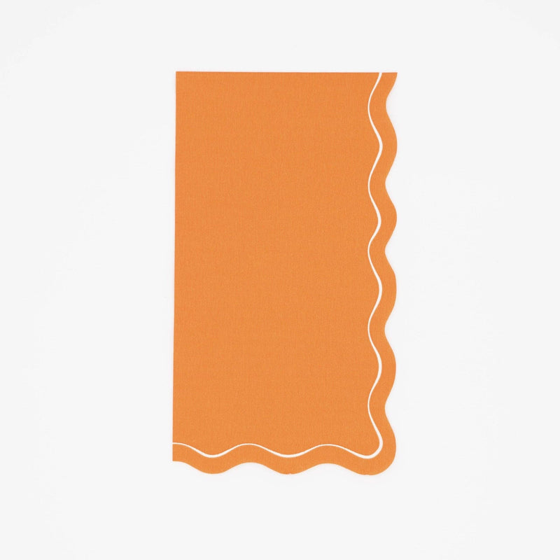 Orange fall paper guest towel in solid pumpkin with a cream wavy scalloped edge, flat view on white background.