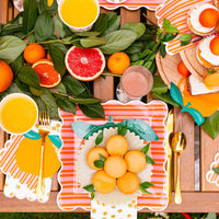 Orange shaped napkins layered into a bright summer tablescape.
