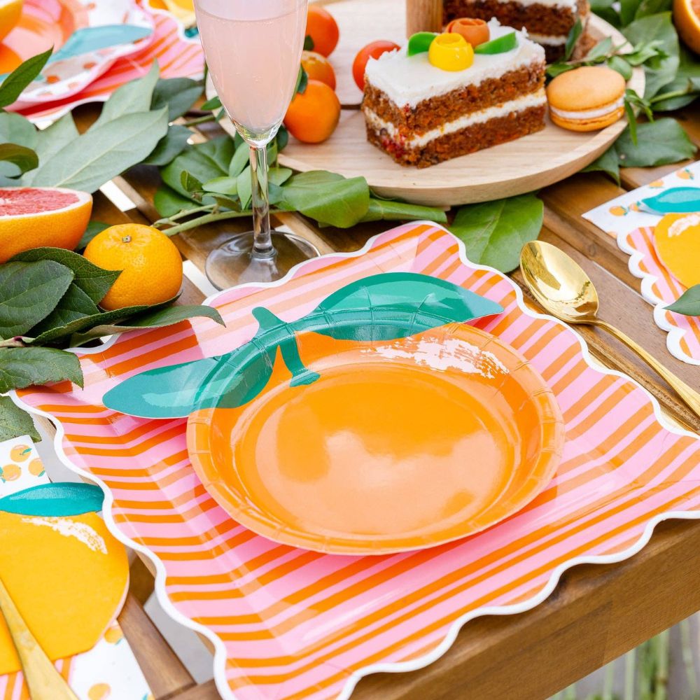Orange shaped plate layered on orange and pink striped plate.
