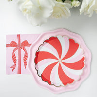 Overhead shot of a single Christmas dessert plate and pink napkin on a white background.