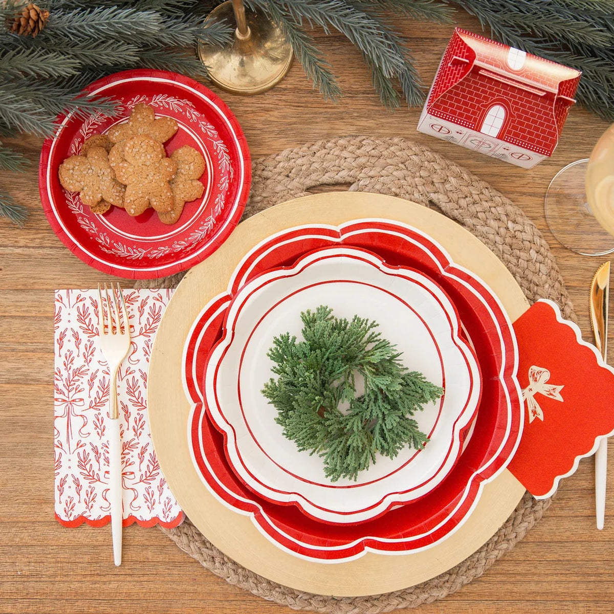 Overhead view of layered holiday plates and the paper dinner napkins set at a holiday place setting with gold cutlery.