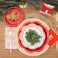Overhead view of layered holiday plates and the paper dinner napkins set at a holiday place setting with gold cutlery.