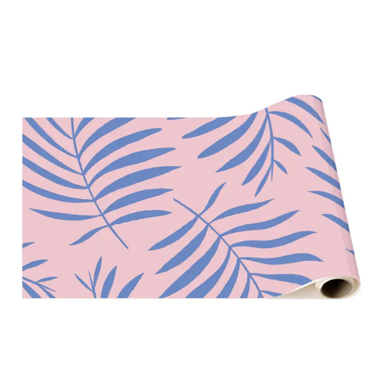Rolled pink table runner with cobalt palm frond pattern showing thickness and paper texture.