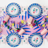 Tropical table with blue‑pink leaf runner, striped plates, and Palm Beach napkins at each setting.