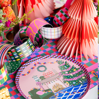 Styled holiday tablescape showing the paper chain garland with a paper fan, checkered plates, and colorful holiday décor.