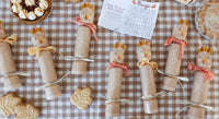 Decorative paper chickens on a checkered tablecloth with cracker pulled open showing the die, game, and paper crown inside.