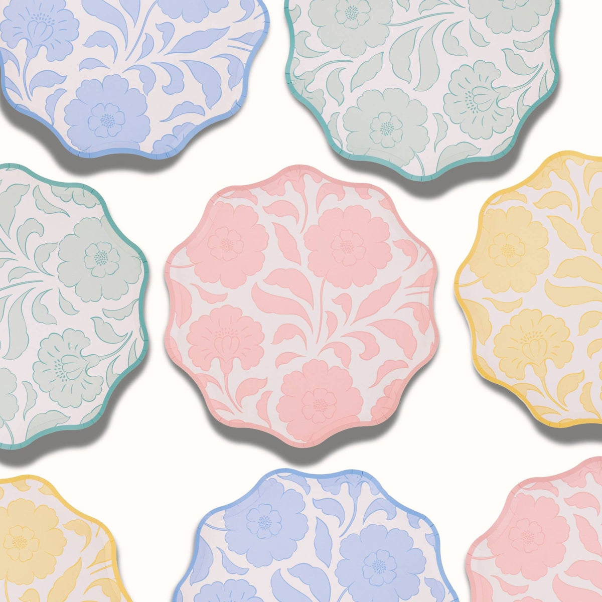 Overhead close-up of the four floral colorways overlapping, showing the block-print bloom and wavy scalloped edges.