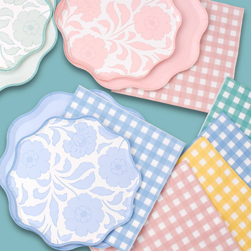Pastel floral scalloped plates layered with coordinating pink, blue, and yellow gingham paper napkins.