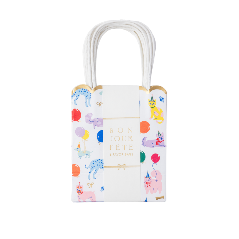 Front-facing studio shot of a white paper favor bag featuring pastel watercolor cats and dogs with a gold foil scalloped top edge and white paper handles.