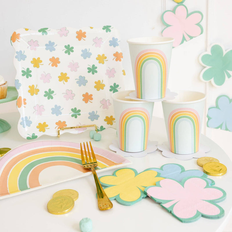 Pastel rainbow shaped paper plates styled on St. Patrick’s Day party table with shamrock decor