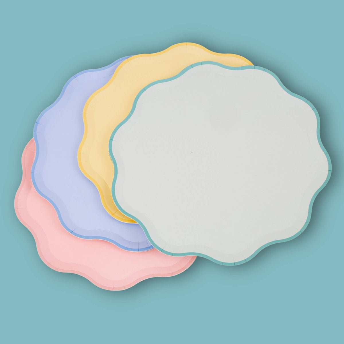 Four pastel scalloped paper plates in pink, sage, yellow and lilac grouped together