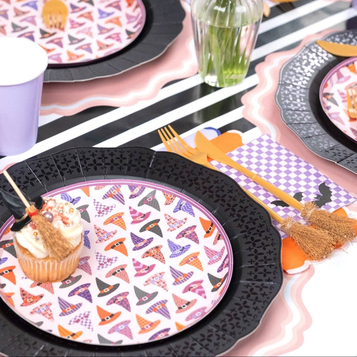 Pastel Halloween tablescape showing a pink witch hat plate layered perfectly over the large black die-cut scalloped paper plate.