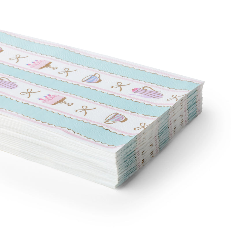 Stack of folded patisserie guest towels showing the teacup-and-cake print and pastel stripes from an angle.