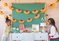 Two children at styled back to school party table with pencil shaving banner hanging above chalkboard, cake, and classroom-themed decor